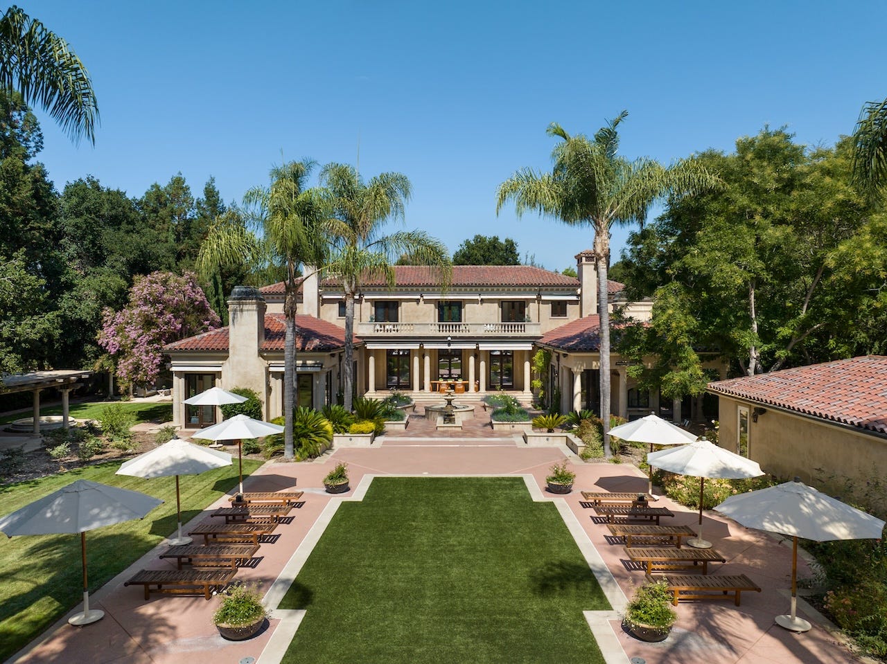 A mansion in Atherton, California, facing onto a green lawn and surrounded by trees.