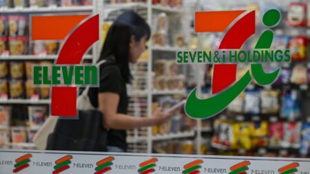 7-Eleven’s parent company cuts full-year earnings forecast, presses ahead with restructuring