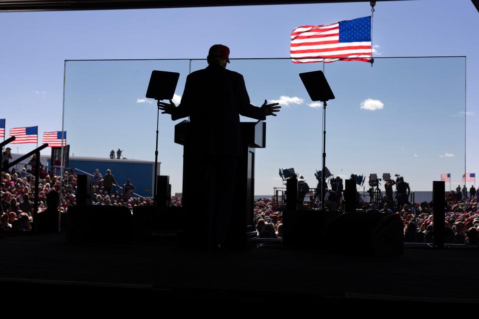 Republican presidential nominee and former President Donald Trump speaks from behind a glass protective barrier during a rally at Dodge County Airport on October 06, 2024 in Juneau, Wisconsin.